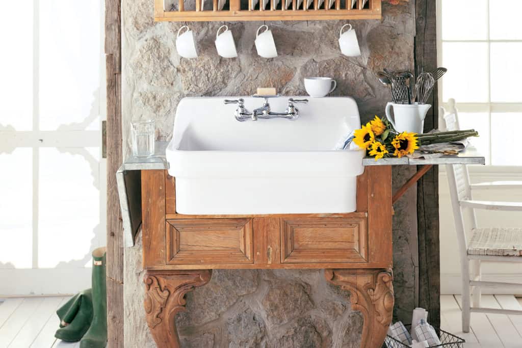 This modern farmhouse interior design features white porcelain basin and chrome faucet on a vintage wooden cabinet.