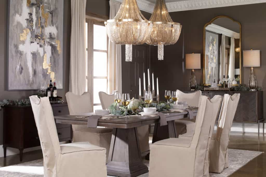 Traditional interior design dining room featuring a rustic wooden table, crystal chandeliers, dark walls, and stylish accents