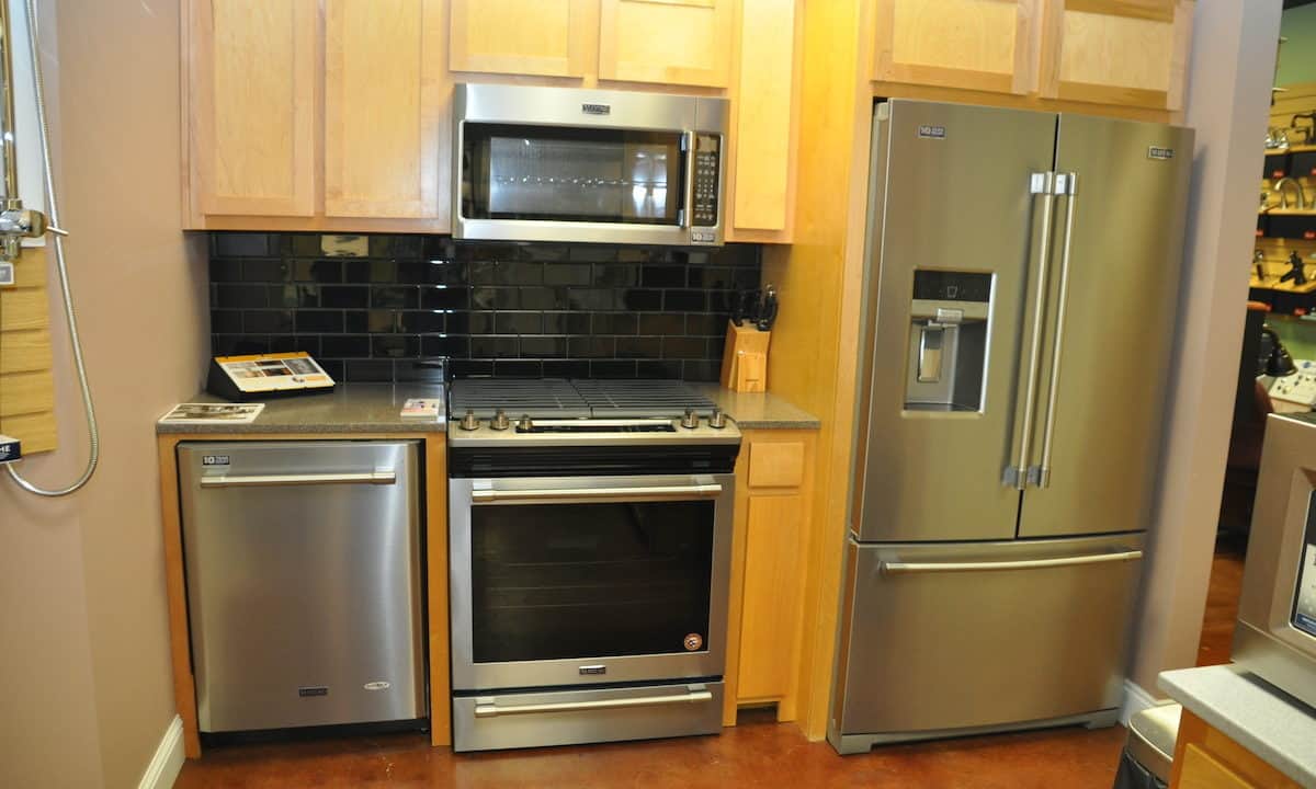 Kitchen showroom display featuring appliances, cabinet and hardware, with countertops