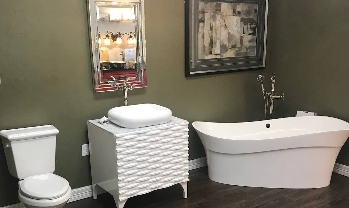Showroom display of a bathroom featuring a bathtub, sink, toilet, and home decorations