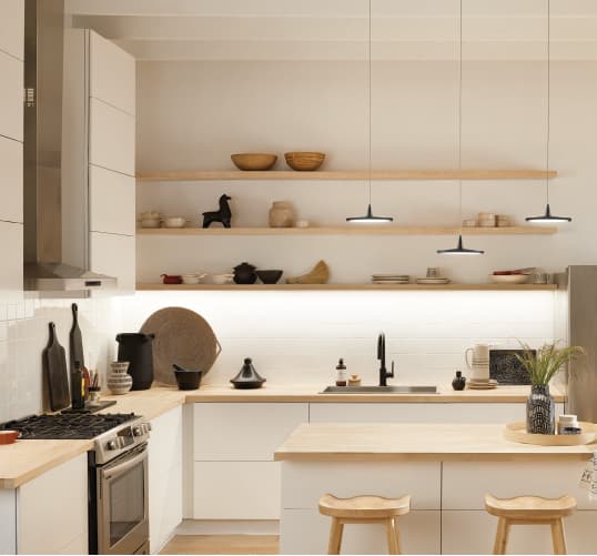 minimalist pendant kitchen lighting surrounded by natural wood counters and sleek white cabinetry. Get more kitchen design inspiration at Coburn's Kitchen & Bath Showroom.