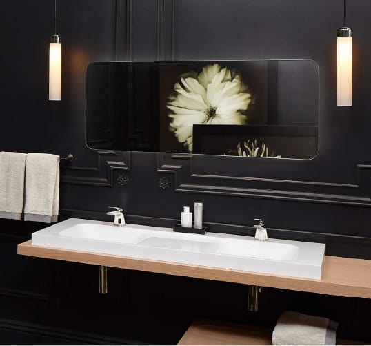 a frameless vanity mirror surrounded by dark wall paneling and light wood make this space the perfect bathroom inspiration for fans of the bold.