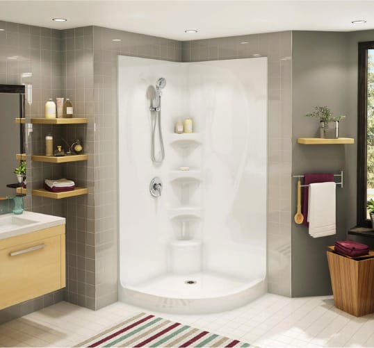 a rounded corner shower with white base and surround, accented with grey walls and white flooring. Get more bathroom design ideas at Coburn's Kitchen & Bath Showroom
