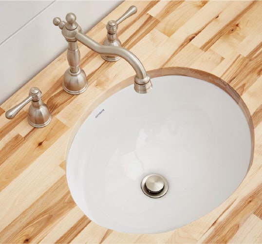 An oval undermounted bathroom sink surrounded by textured wood that is perfect for your bathroom renovation ideas list.