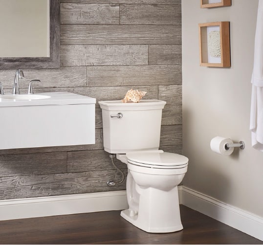 Traditional bathroom inspiration featuring an elongated bowl toilet accented by wood paneling.