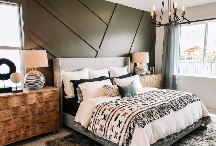 Rustic farmhouse bedroom design ideas from Coburn’s Showroom. Featuring wood grain dressers, an olive green feature wall, natural lighting and a large bed with green and gray accent features.