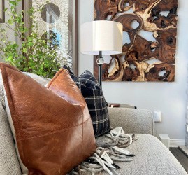 Transitional living room remodel inspiration, including faux leather throw pillows, wooden wall art and foliage for a pop of color.