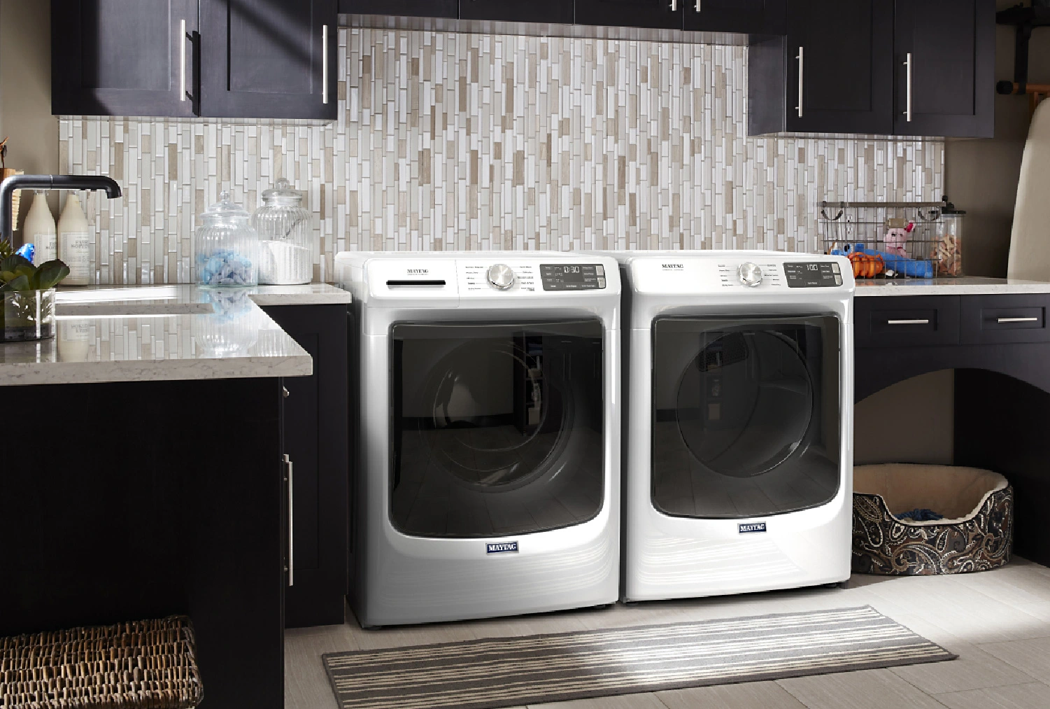 A stylish laundry room design featuring a front load washer and dryer set, laundry room sink and additional storage for kids and pets.