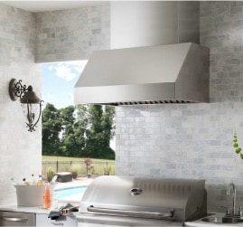 An enclosed outdoor cooking area complete with grill and hood vent, all overlooking a pool. Get more backyard makeover ideas at a Coburn's Showroom near you.